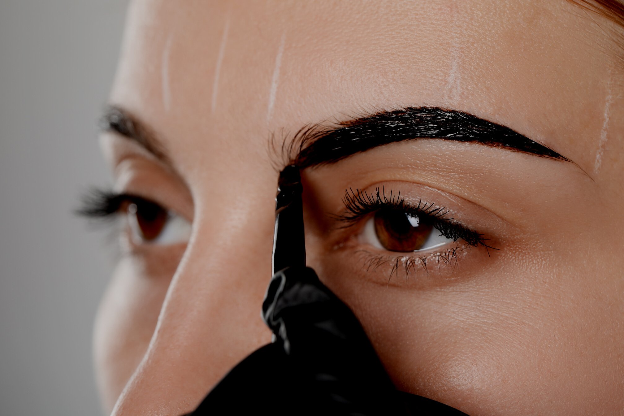 Beautician Applying Tint during Eyebrows Correction Procedure on